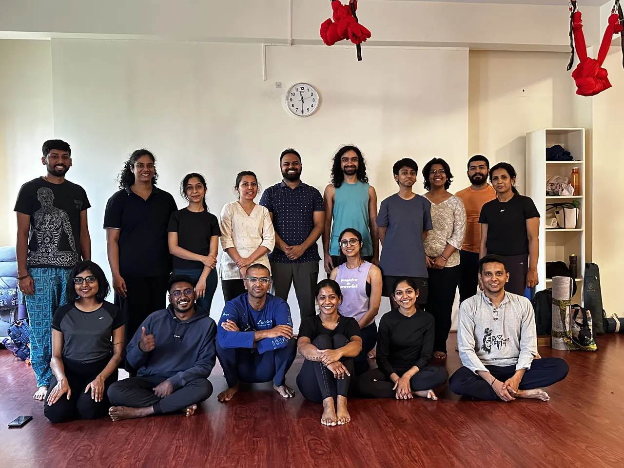 The Yoga Mandala community gathered for a group photograph in a studio, some standing and some seated on the floor