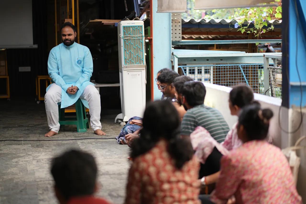 Praṇav Śāstrī seated on a stool before a group of students listening