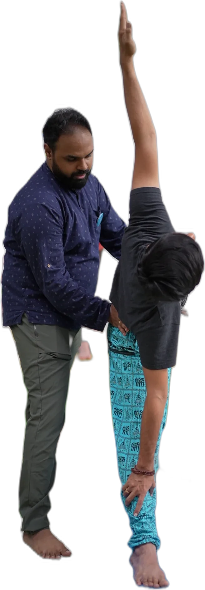Praṇav Śāstrī steadying a student's hip as she reaches into a standing side bend