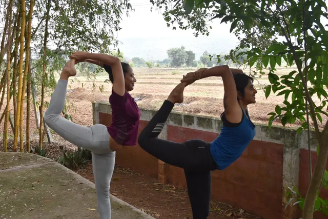 Two practitioners in dancer’s pose side by side