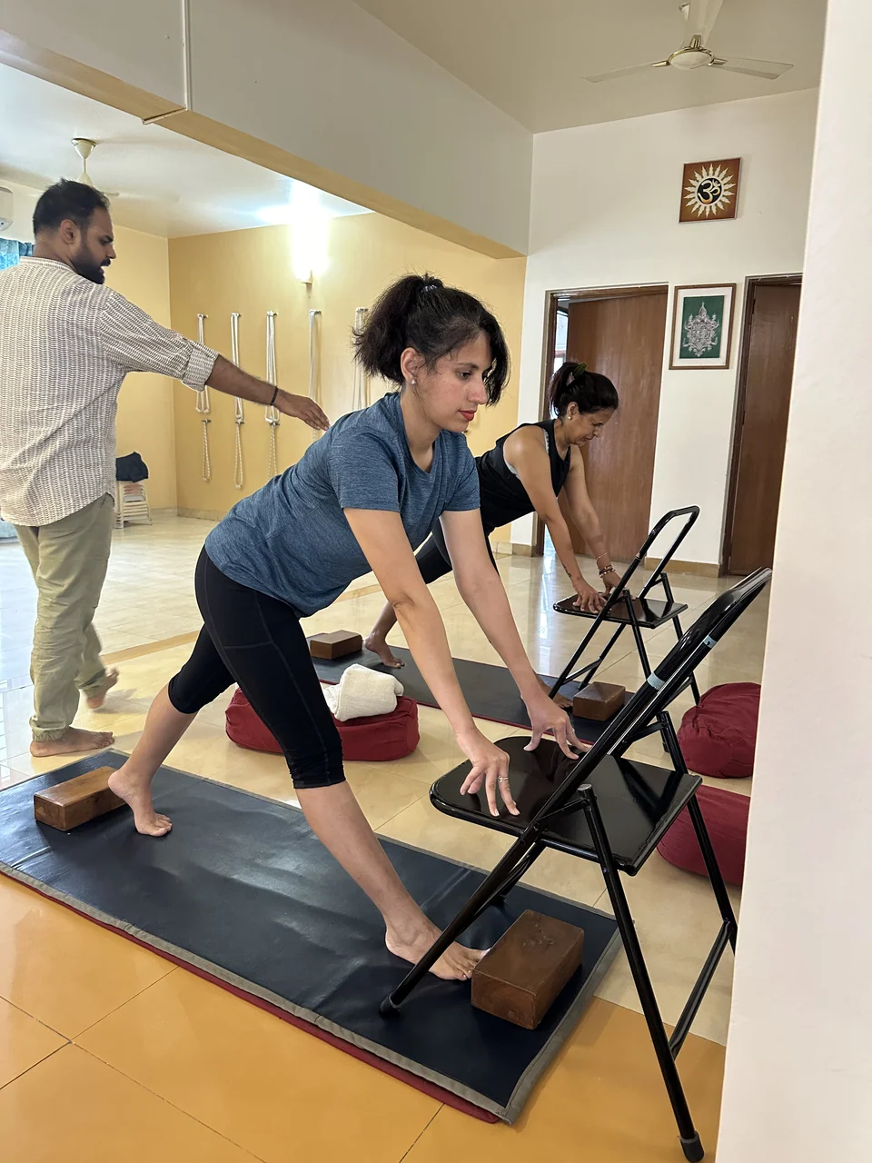 A man reaching out to adjust the back of a woman folding forward over a folding chair