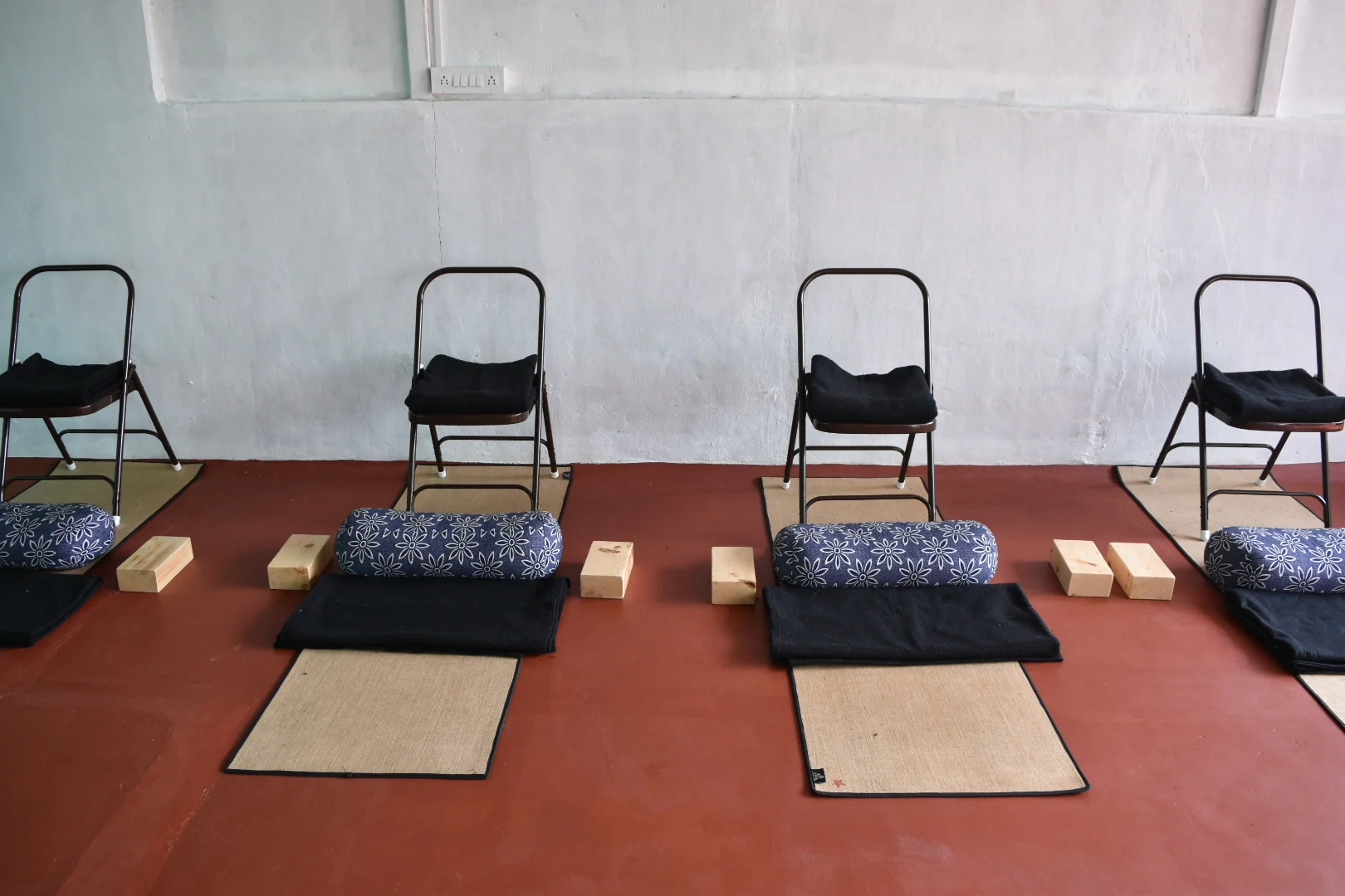 A close view along a row of mats with folded blankets, bolsters, blocks and folding chairs