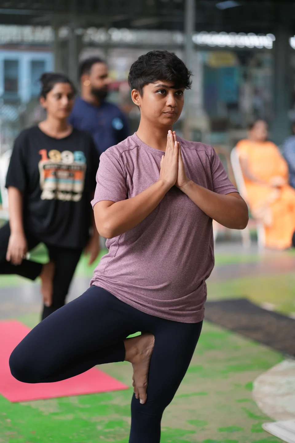 A practitioner balancing on one leg with palms together at the chest.