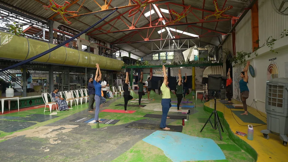 Wide view of a group practising with arms raised under a high steel roof